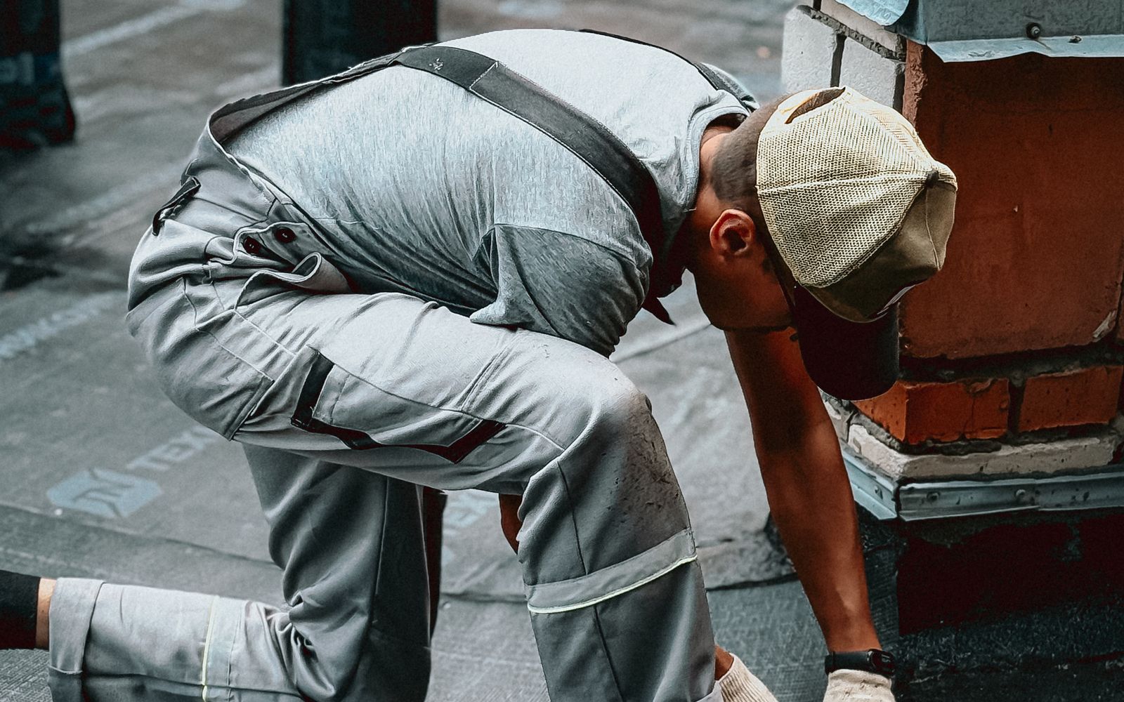 Roofer bent low over a roof surface beside a chimney