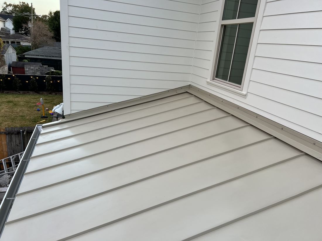 Low metal roof meeting the siding of a house wall