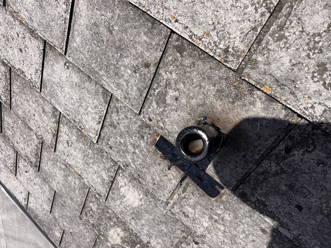 Weathered shingles around a pipe boot, up close