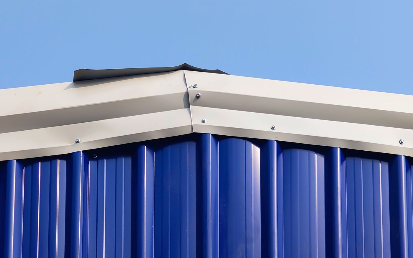 Blue ribbed metal wall under a white roof edge