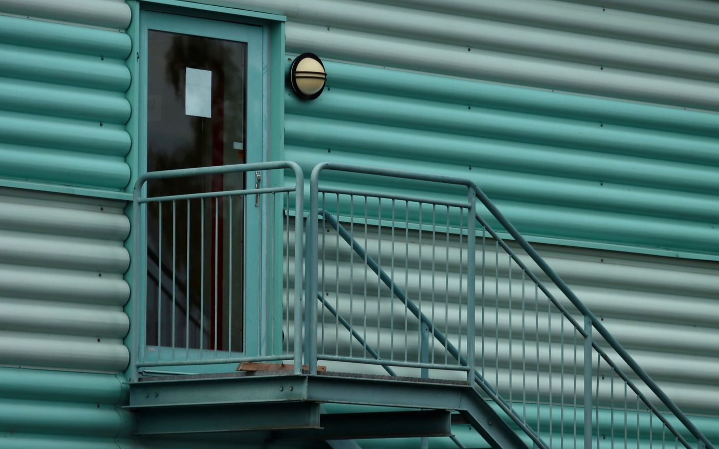Green ribbed metal cladding with a steel stair and door