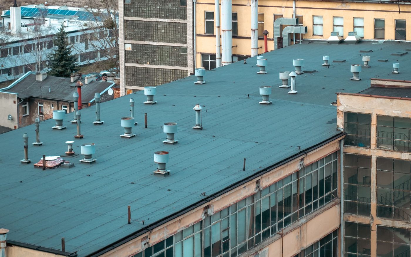 Flat teal rooftops dotted with vents on an industrial building