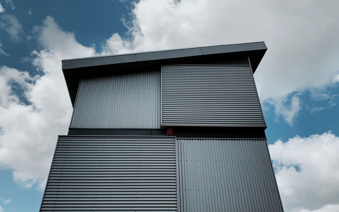 Metal-clad building rising against a cloudy sky