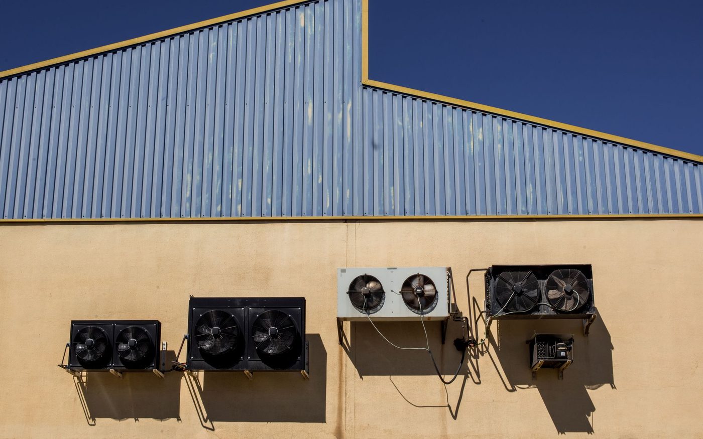 Air conditioning condensers mounted on the wall of a warehouse