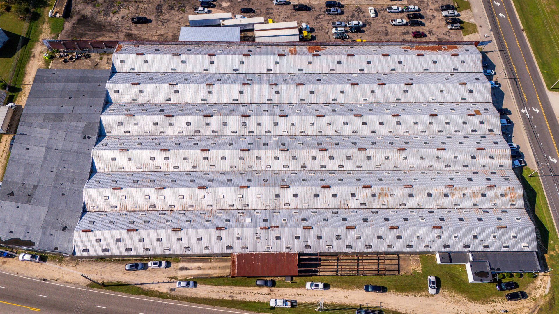Large warehouse roof and parking lot seen from above