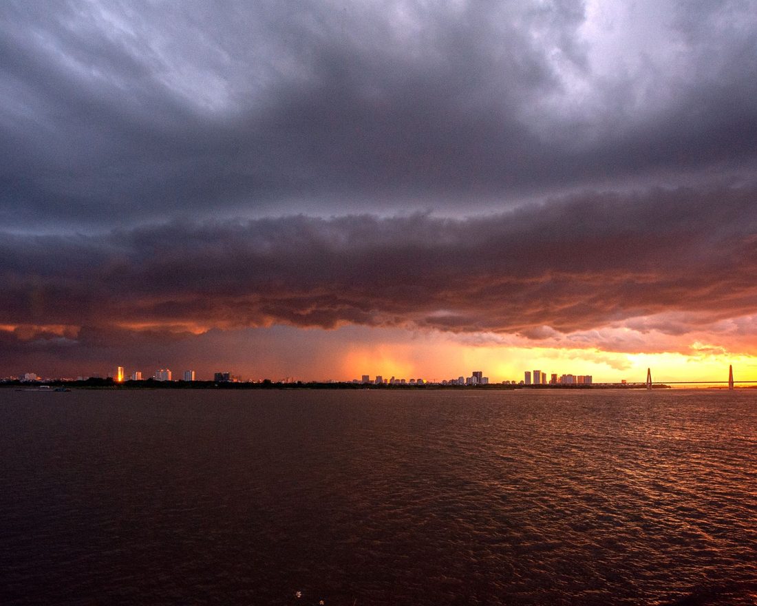 Storm clouds rolling in over open water at sunset