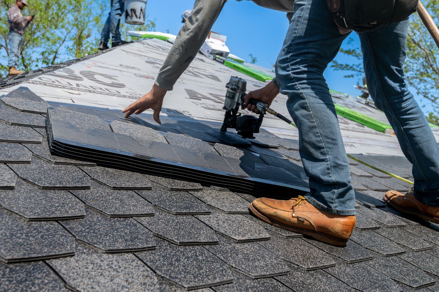 Roofer fastening architectural shingles with a nail gun