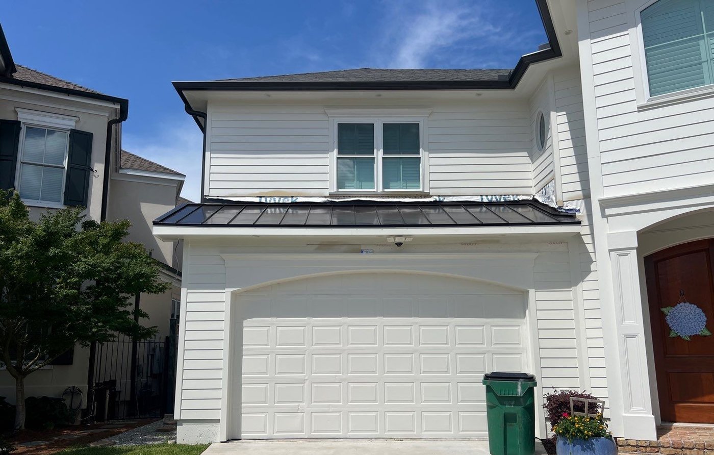 Finished two story house with a dark standing seam porch roof and a clear driveway