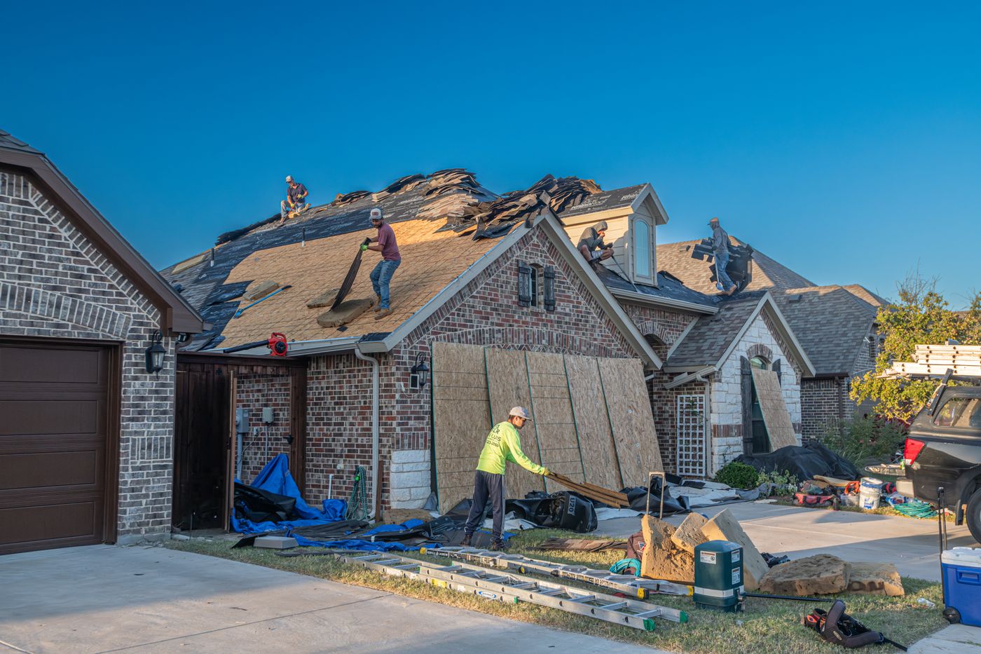 Crew clearing an old roof from a brick house