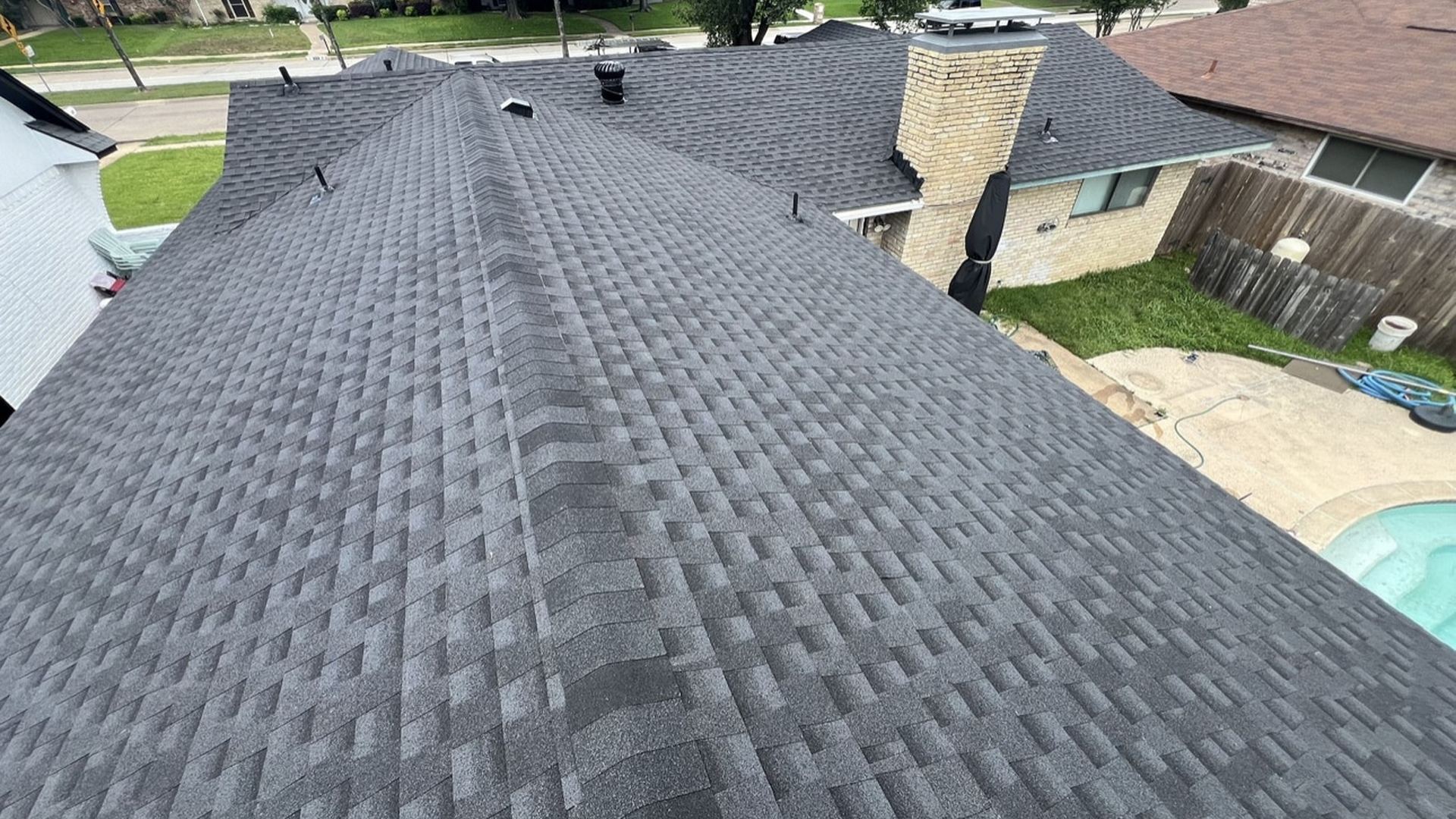 Shingle roof ridge seen from above, with a chimney beyond