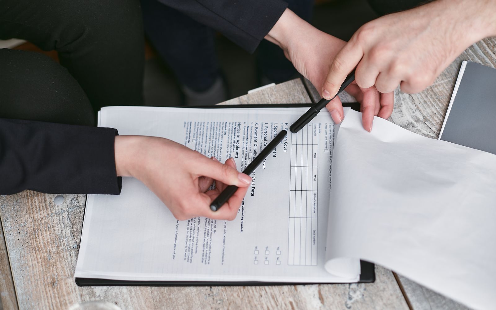 Hand holding a pen over a printed form on a clipboard