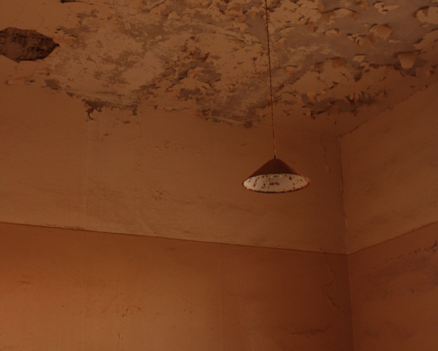 Water-stained ceiling above a pendant light in a room corner