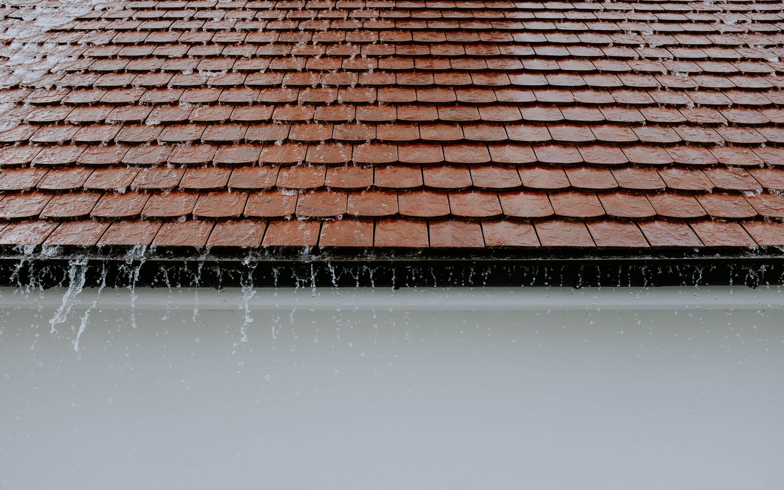 Rain pouring over the edge of a tiled roof