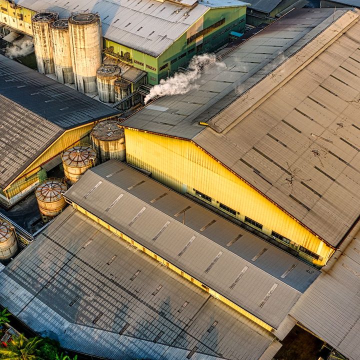 Industrial roofs lit yellow by low sun, seen from above