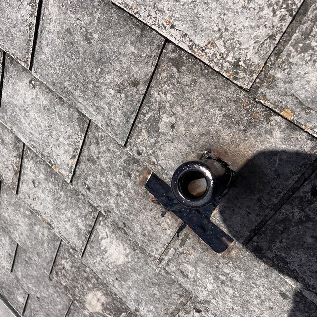 Weathered shingles around a pipe boot, up close