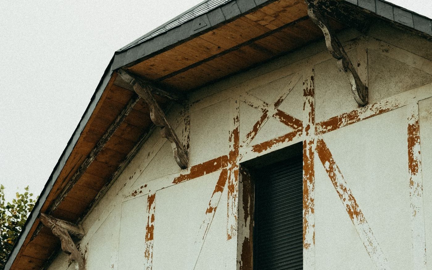Weathered gable of a house with peeling paint and rust stains