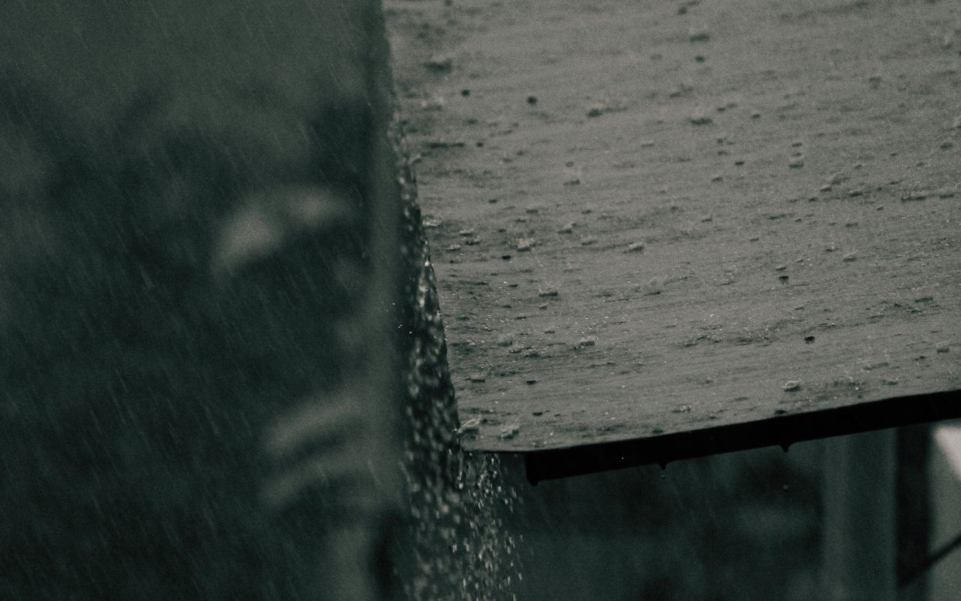 Rain running off the edge of a roof, in black and white