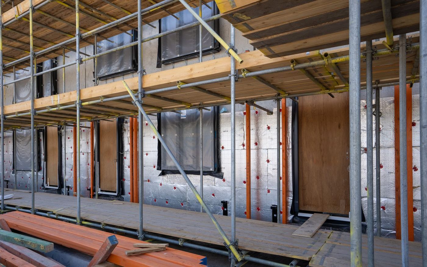 Scaffolding around a wall covered in insulation boards