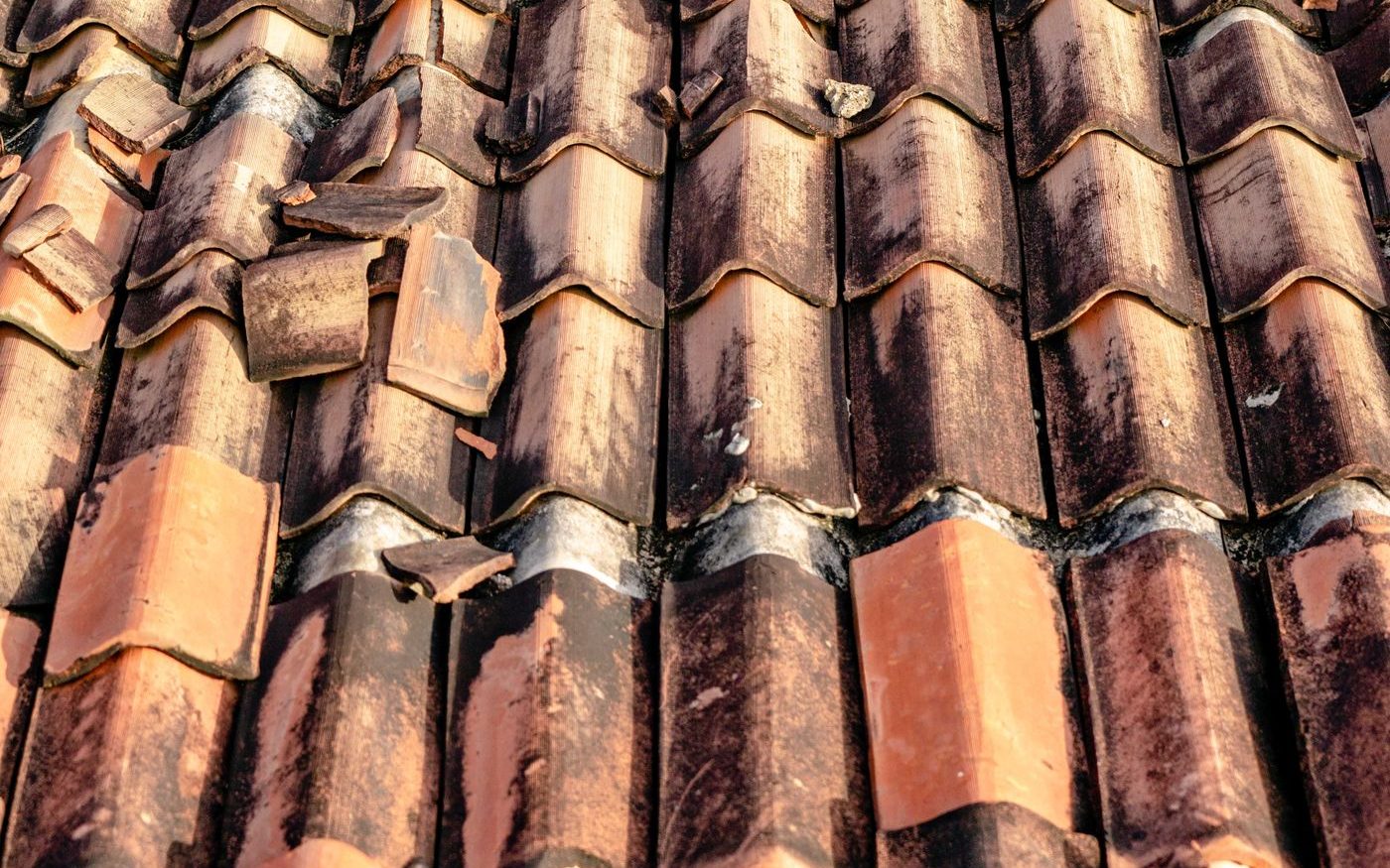 Clay roof tiles cracked and slipped out of their rows