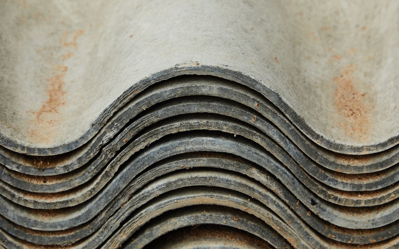 Stack of old curved roofing sheets, weathered at the edges