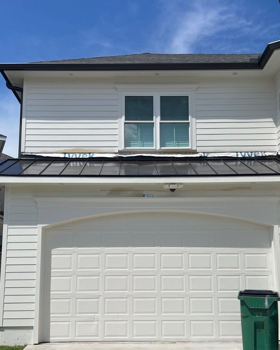 White two story house with a dark porch roof over the garage