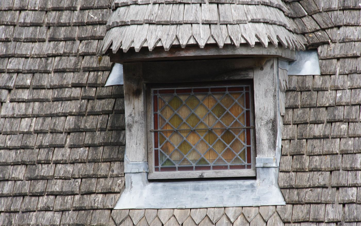 Leaded window framed by gray wooden shakes