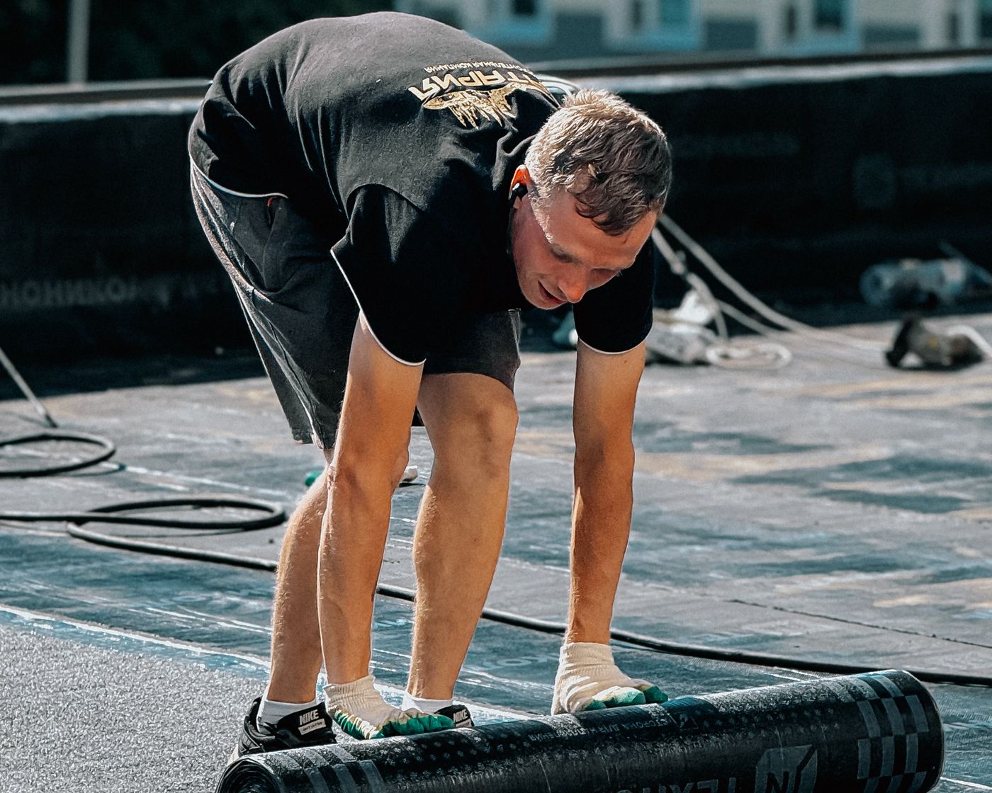 Worker rolling out membrane on a low-slope roof