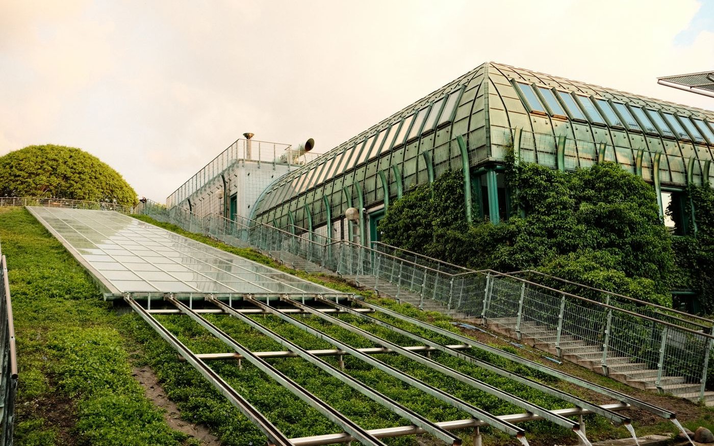 Sloped planted roof beside a glass conservatory