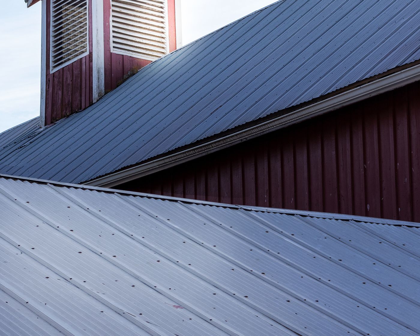 Dark standing seam metal roof on a red house