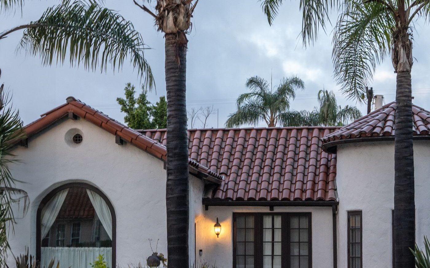 White house with a red tile roof and palm trees