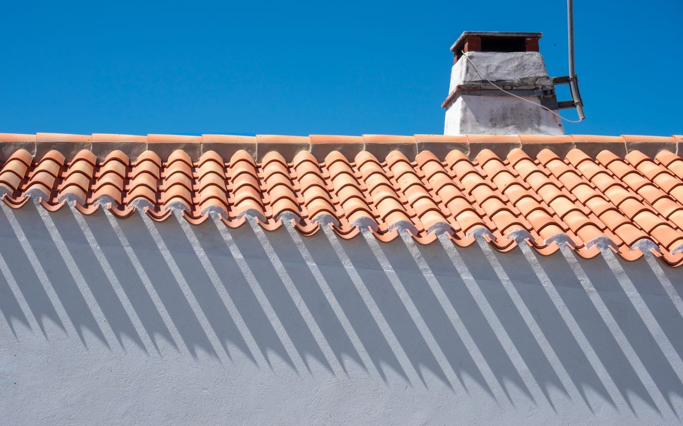 Barrel tile edge and a white chimney above a white wall